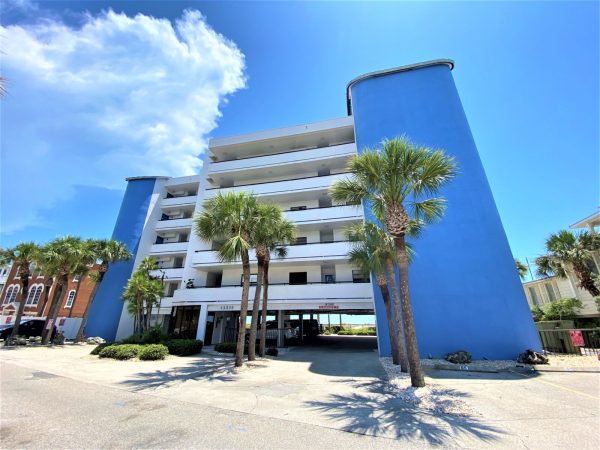 A white multi-story resort property standing tall against a bright blue sky.