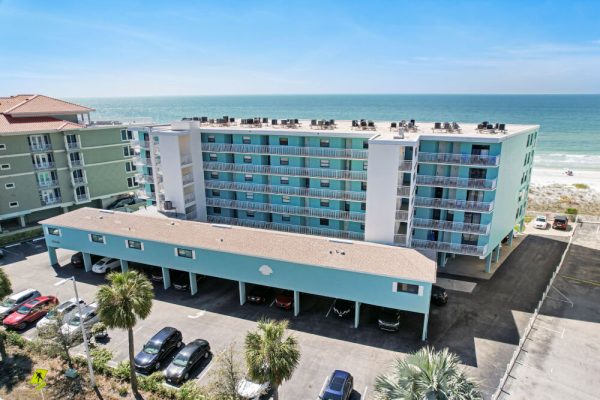 A blue multi-story beachfront condo property situated along white sand.