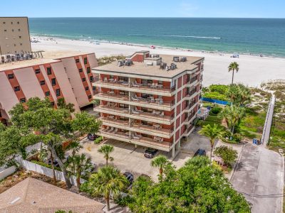 Exterior view of a multi-story brick resort building facing the beach sand.