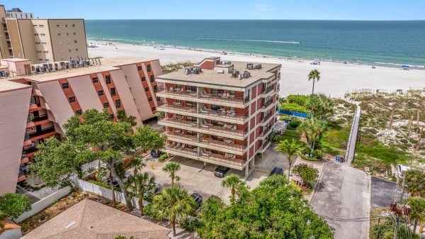 Exterior view of a multi-story brick resort building facing the beach sand.