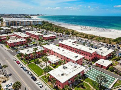 Aerial perspective of a beachfront resort complex surrounding a pool and green lawns.